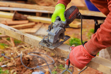 Carpenter hands working on cutting wooden beam with hand saw - obrazy, fototapety, plakaty