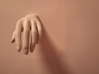 Mannequin hand on a brown background. Space for text.
