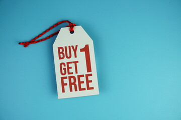 Top view of Buy one get one free text on tag sale flat lay on blue background