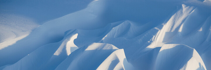 Snow texture. Wind sculpted patterns on snow surface. Wind in the tundra and in the mountains on the surface of the snow sculpts patterns and ridges. Arctic, Polar region. Winter panoramic background. - 778597243