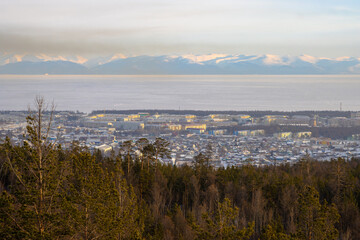 Severobaikalsk city, Republic of Buryatia, Siberia, Russia. View of the city of Severobaikalsk, located on the coast of Lake Baikal. Winter landscape. Snow-capped mountains in the distance.