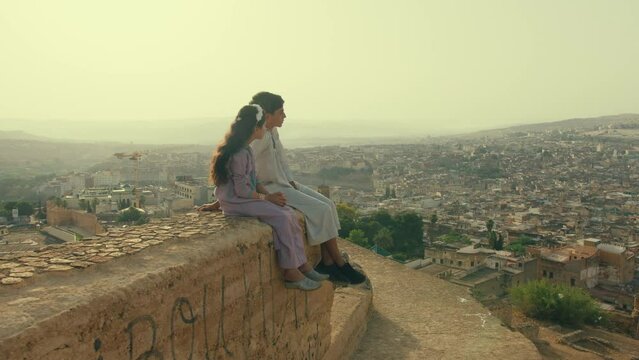 Kids Overlooking Old City of Fes in Morocco while sitting on a wall