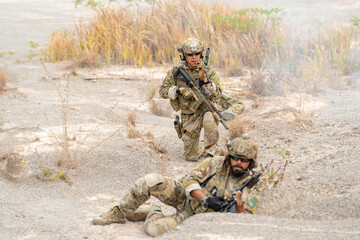 One of soldier or military lie down and look at camera and the other one sit in the position of ready to fighting during outdoor practice.