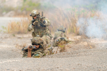Fototapeta premium Group of military or soldiers hold the gun and point to the front and ready to fight with enemy during outdoor practice.