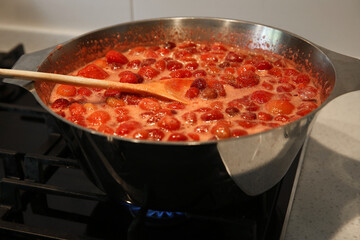 Cooking strawberry jam in a large bowl at home