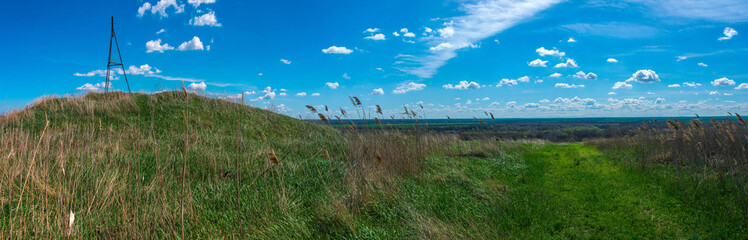 an ancient burial in the form of a mound with a triangulation sign on top, in a field on the high bank of the Kuban near the city of Ust-Labinsk (South of Russia) on a sunny day in early spring - obrazy, fototapety, plakaty