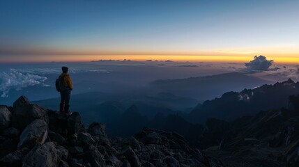 Solo traveler reaching the summit at dawn, embracing the serene beauty of a panoramic mountain view.