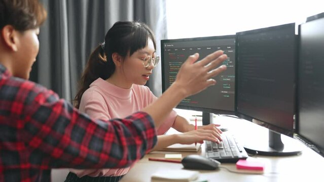 Slow motion back end software developer engineer for computer programming working together on debugging writing computing code, solving complex algorithms display on monitor in office. Burgeoning