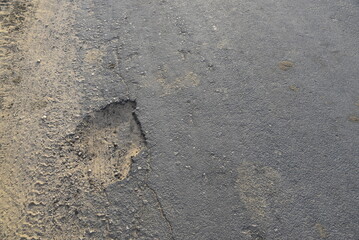 Bad road, cracked asphalt with potholes and big holes. Potholes on the road with stones on the asphalt. The asphalt surface is destroyed on the road. Bad condition of the road - 778663814