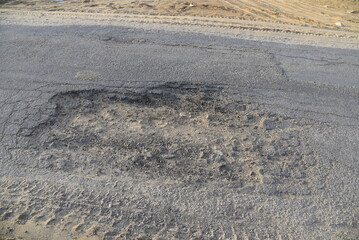 Bad road, cracked asphalt with potholes and big holes. Potholes on the road with stones on the asphalt. The asphalt surface is destroyed on the road. Bad condition of the road - 778663825