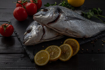 Sea bream or dorado sea fish herbs on dark slate background Top view 
