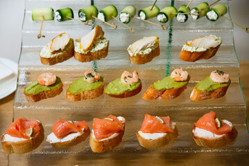 Assorted Gourmet Canapés with Salmon, Avocado, and Shrimp. Elegant selection of canapés topped...