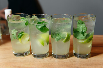 Fresh Mojito Cocktails with Lime and Mint. Four glasses of classic mojito cocktails, garnished with...