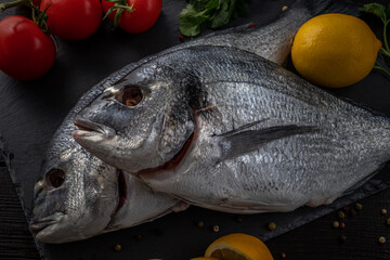 Sea bream or dorado sea fish herbs on dark slate background Top view 