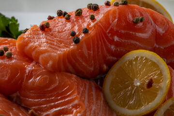 Fresh raw salmon fillet with cooking ingredients, herbs and lemon on black slate