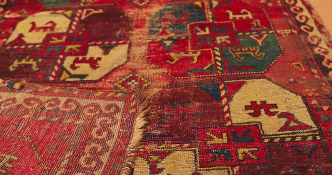 Close up shot of an old shabby handmade carpet made by Samarkand masters using ancient technology. It is covered with national patterns and ornaments. Uzbekistan.