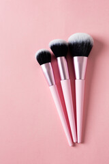 Minimal set of foundation brushes, base concealer and powder on pink background