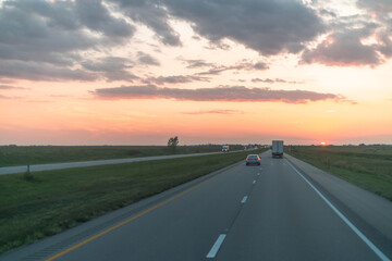 Highway Leading into the Sunset with Vehicles and Overpass in View