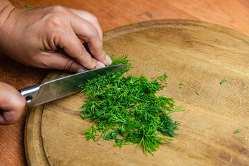Woman cutting green dill on the cutting board