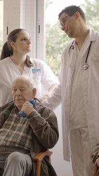 Distracted doctors talking while senior people exercising in geriatric