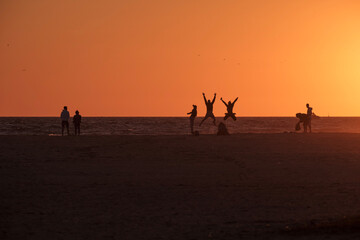 Playa de Tarifa, Cádiz, atardecer en la playa, personas disfrutando de los últimos rayos de sol en la arena de la palya, luz dorada - obrazy, fototapety, plakaty