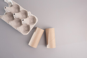 Eco-Friendly DIY: Unfinished egg carton box and toilet paper roll for recycled craft ideas. Close-up, top view on grey