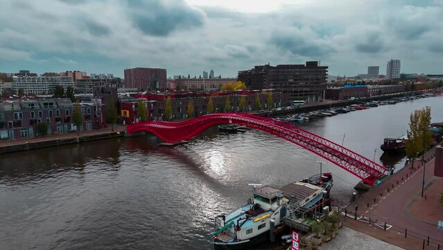 Aerial drone view of modern footbridge Python Bridge at Eastern Docklands neighborhood of Amsterdam Netherlands. High quality 4k footage