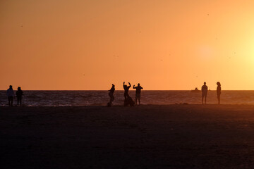 Playa de Tarifa, Cádiz, atardecer en la playa, alegria y fiesta, personas disfrutando de los últimos rayos de sol en la arena de la palya, luz dorada - obrazy, fototapety, plakaty