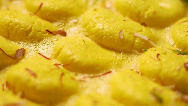 Delicious Rasmalai, Rossomalai, Roshmolai is popular Indian dessert. chef droping kesar on sweet made with cottage cheese and milk to celebrate festivals of India like Diwali, Holi, Ganesh Chaturthi.