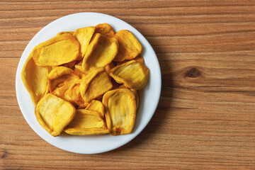 Keripik Sukun or Breadfruit Chips is a food made from breadfruit in a plate on a pine table surface