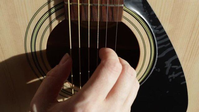 Hands on acoustic guitar, close-up of player's fingers, musical hobby, guitar education