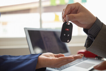 car dealer is handing over car keys to customer after sales contract and installment contract have...
