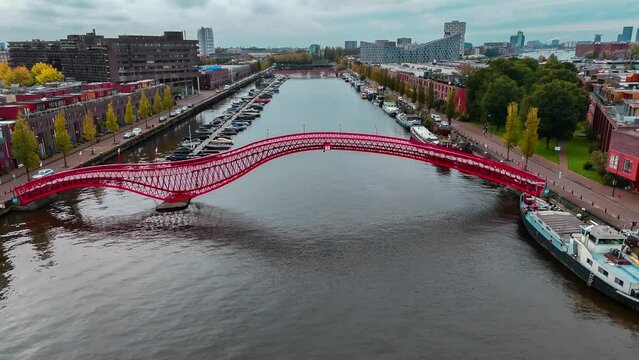 Aerial drone view of modern footbridge Python Bridge at Eastern Docklands neighborhood of Amsterdam Netherlands. High quality 4k footage
