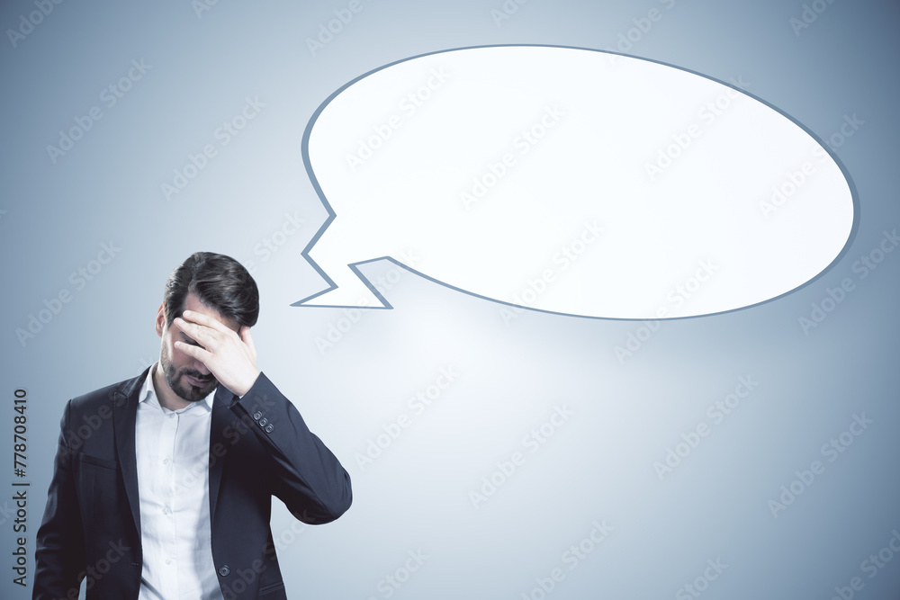 Poster anxious young businessman with empty speech bubble on gray background. opinion and mock up place.