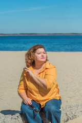 Vacation mood. Plus size happy mature lady wear yellow shirt and blue pants at beach , spring - summer clothes collection