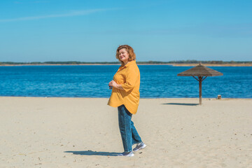 Vacation mood. Plus size happy mature lady wear yellow shirt and blue pants at beach , spring -...
