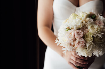 Beautiful wedding bouquet in hands of the bride. Trendy and modern wedding flowers. Soft pastels