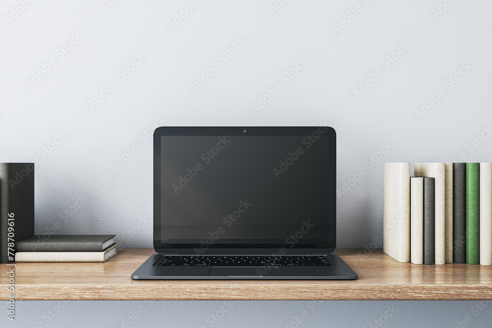 Poster close up of creative wooden designer desk with books and empty mock up laptop screen on white concre