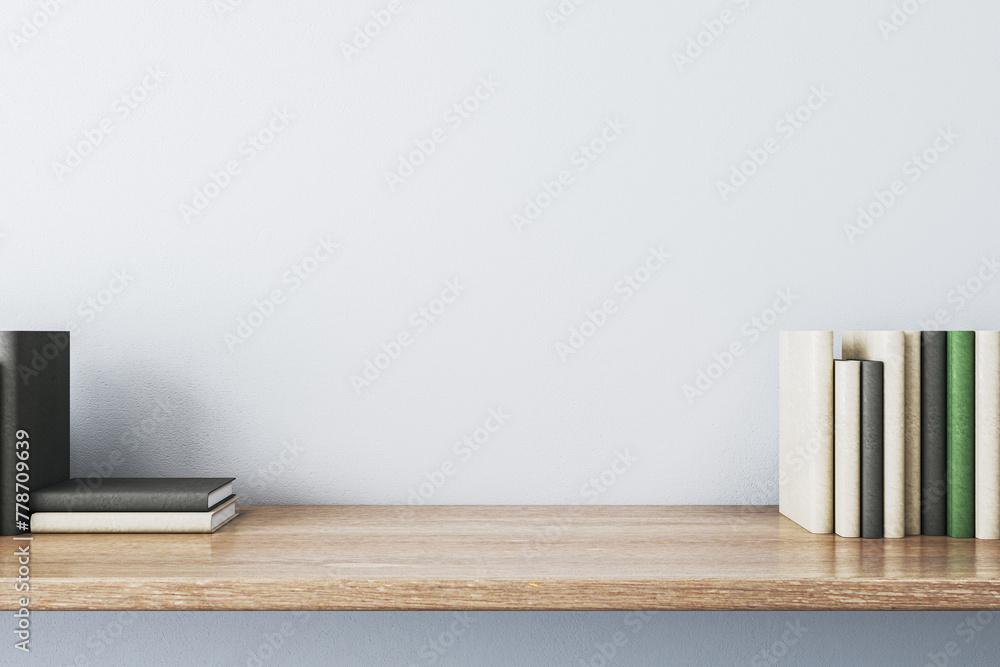 Poster close up of creative wooden designer desk with books and empty mock up place on white concrete wall.