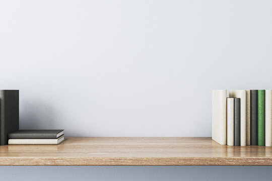 Close up of creative wooden designer desk with books and empty mock up place on white concrete wall. 3D Rendering.