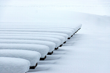 wooden benches covered with a thick blanket of snow, play of light and shadows, rhythm - obrazy, fototapety, plakaty