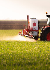 Tractor spraying pesticides wheat field. - 778728401