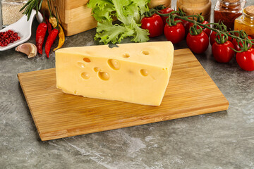 Swiss Maasdam cheese triangle over board