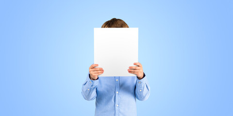 Little boy covering face with blank placard