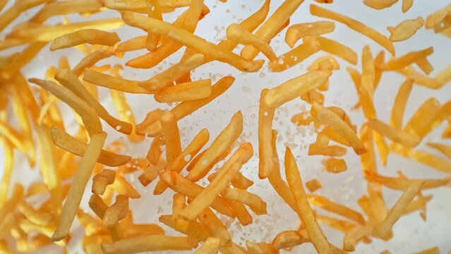 Super Slow Motion Shot of French Fries and Salt Flying Towards Camera on White at 1000fps.