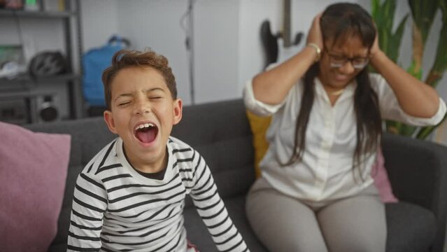 Laughing boy covering ears with frustrated woman in a cozy living room