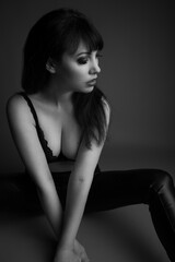 Black and white studio portrait of a beautiful caucasian model in her 30s wearing a black lace bra...