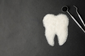 Dentist tools mirror and teeth made of sugar on a black background - 778760261