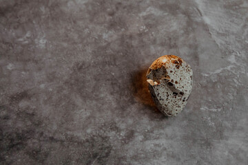 Cracked quail egg with broken shell on grey background