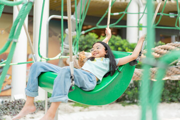 Obraz premium Joyful Asian girl having enjoy and fun playing on a zip line in an adventure park outdoors on the playground.